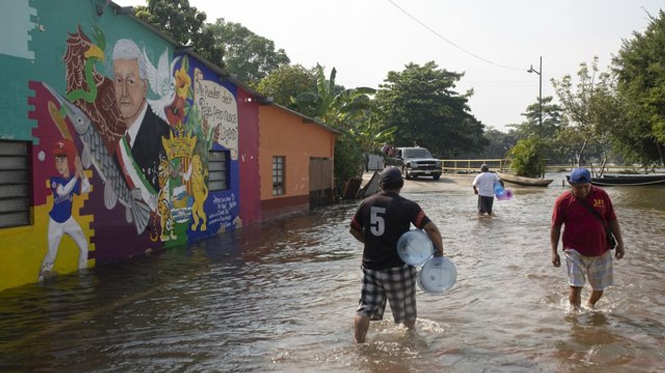 Einwohner gehen auf einer überschwemmten Straße im mexikanischen Tepetitan.
