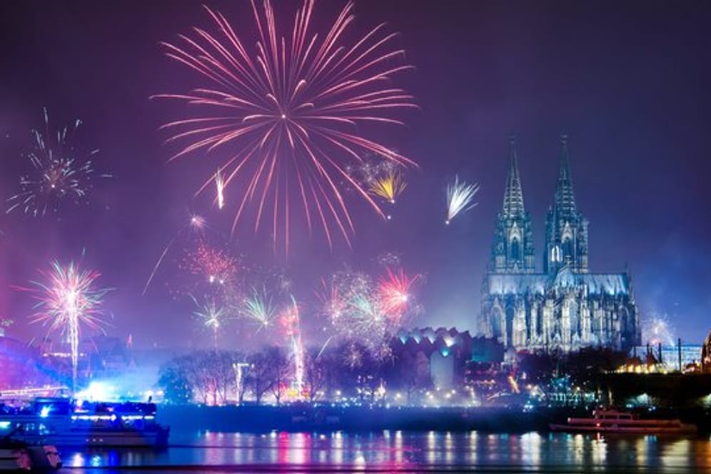Feuerwerk ist in der Silvesternacht am Rhein über dem Dom zu sehen.