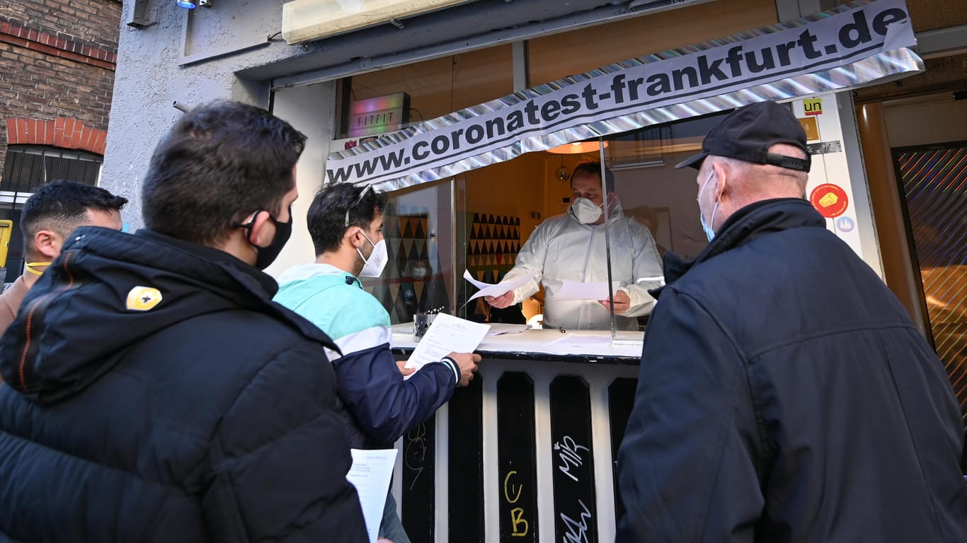 Passanten stehen vor einem Kiosk im Stadtteil Bockenheim, in dem der Internist Georg Siemon einen Corona-Schnelltest anbietet: Der Arzt nutzt den Kiosk nach dessen Schließung für sein privat-ärztliches Testzentrum.