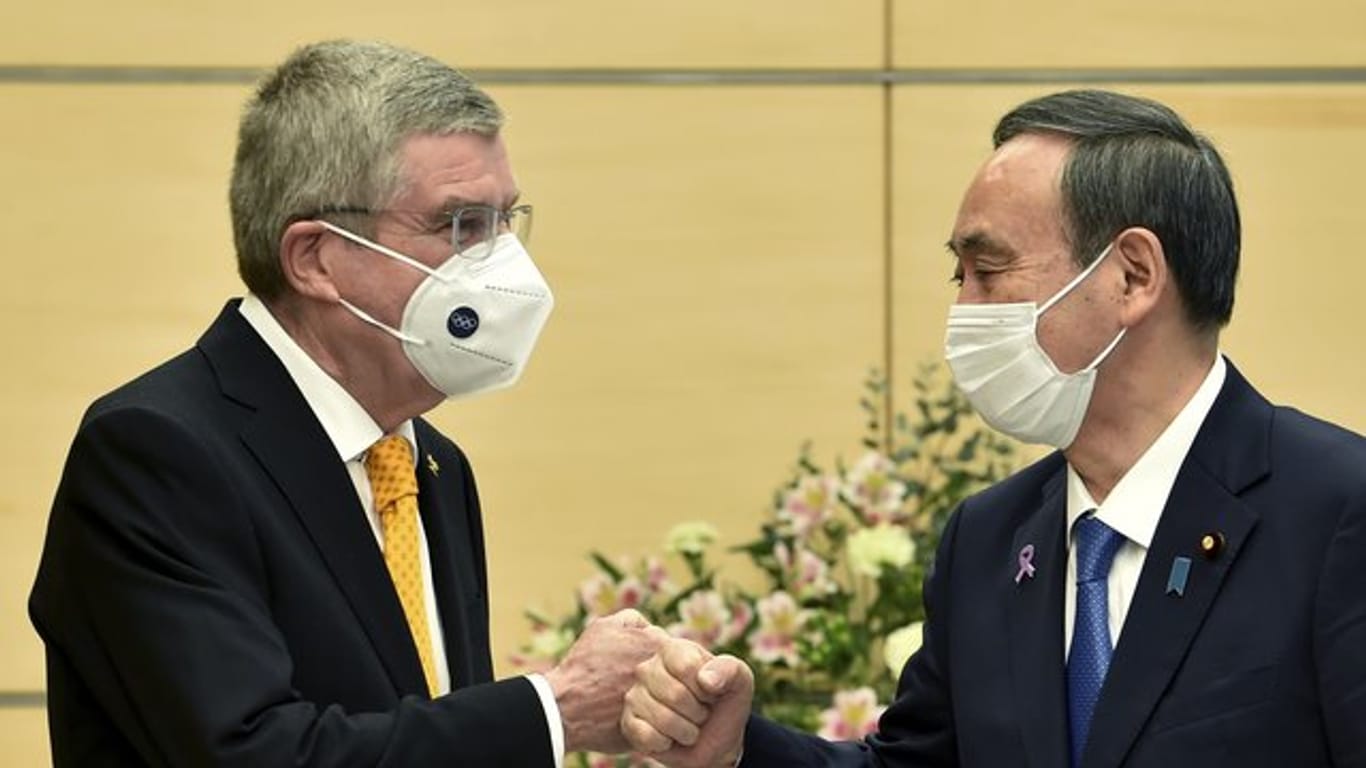 Thomas Bach (l), Präsident des Internationalen Olympischen Komitees, und Yoshihide Suga, Premierminister von Japan, begrüßen sich.