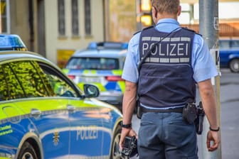 Ein Polizist steht neben einem Einsatzwagen (Symbolbild): In Bonn ermittelt die Polizei wegen Wohnungseinbrüchen.