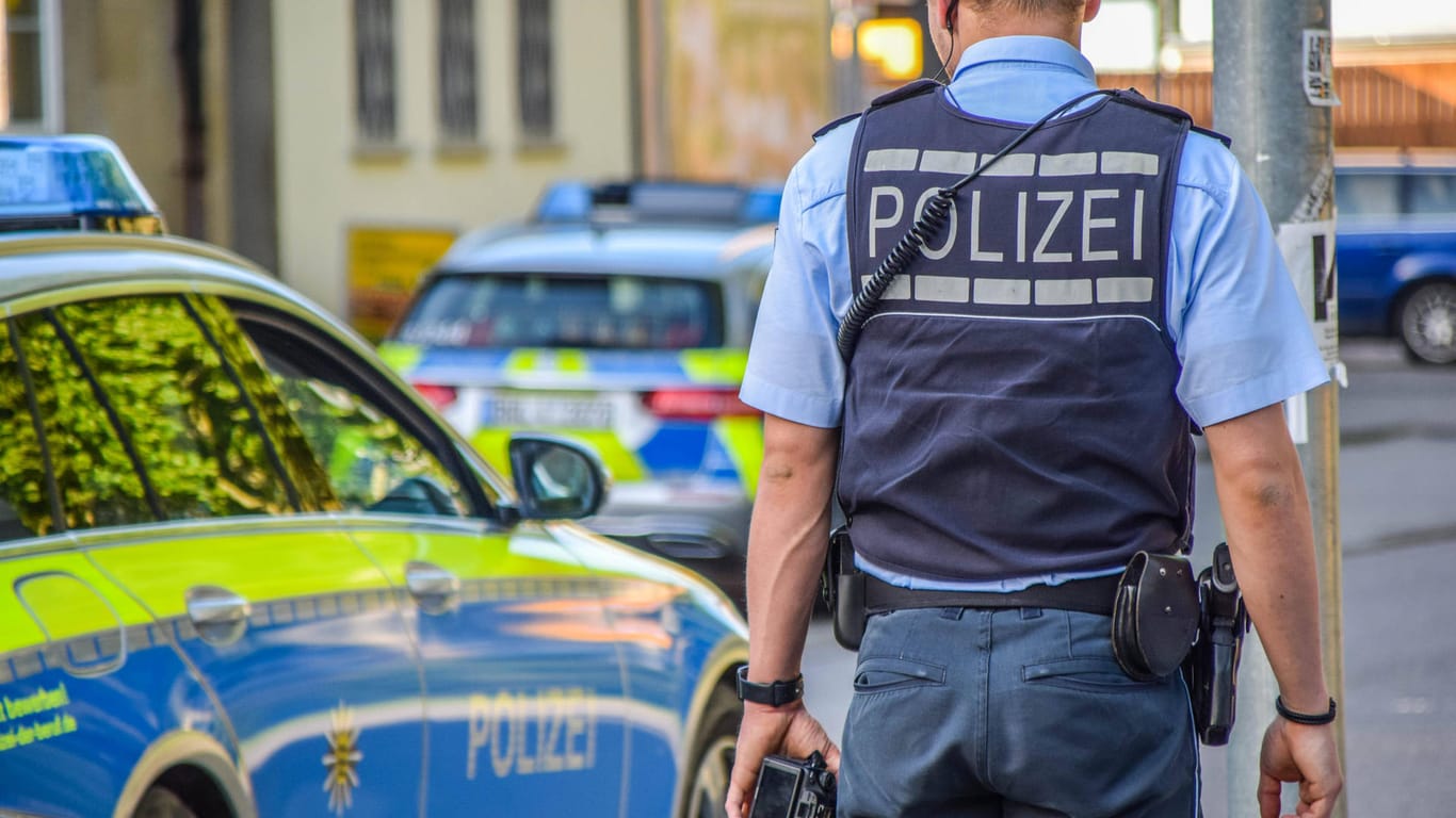 Ein Polizist steht neben einem Einsatzwagen (Symbolbild): In Bonn ermittelt die Polizei wegen Wohnungseinbrüchen.