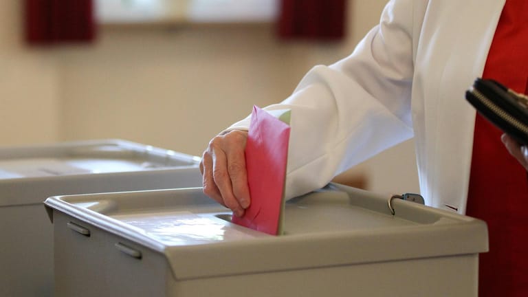 Eine Hand wirft einen Stimmzettel in eine Wahlurne: In Karlsruhe findet am 6. Dezember die Wahl zum Oberbürgermeister statt.