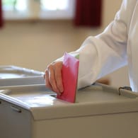 Eine Hand wirft einen Stimmzettel in eine Wahlurne: In Karlsruhe findet am 6. Dezember die Wahl zum Oberbürgermeister statt.