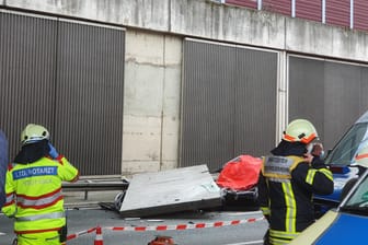 Einsatzkräfte stehen am Unfallort auf der A3 bei Köln: Eine große Betonplatte einer Lärmschutzwand ist auf der Autobahn 3 bei Köln auf einen Wagen gestürzt und hat eine Autofahrerin getötet. Jetzt ermittelt die Staatsanwaltschaft.