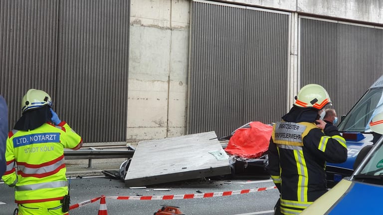 Einsatzkräfte stehen am Unfallort auf der A3 bei Köln: Eine große Betonplatte einer Lärmschutzwand ist auf der Autobahn 3 bei Köln auf einen Wagen gestürzt und hat eine Autofahrerin getötet. Jetzt ermittelt die Staatsanwaltschaft.