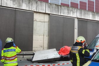 Einsatzkräfte stehen am Unfallort auf der A3 bei Köln: Eine große Betonplatte einer Lärmschutzwand ist auf der Autobahn 3 bei Köln auf einen Wagen gestürzt und hat eine Autofahrerin getötet. Jetzt ermittelt die Staatsanwaltschaft.