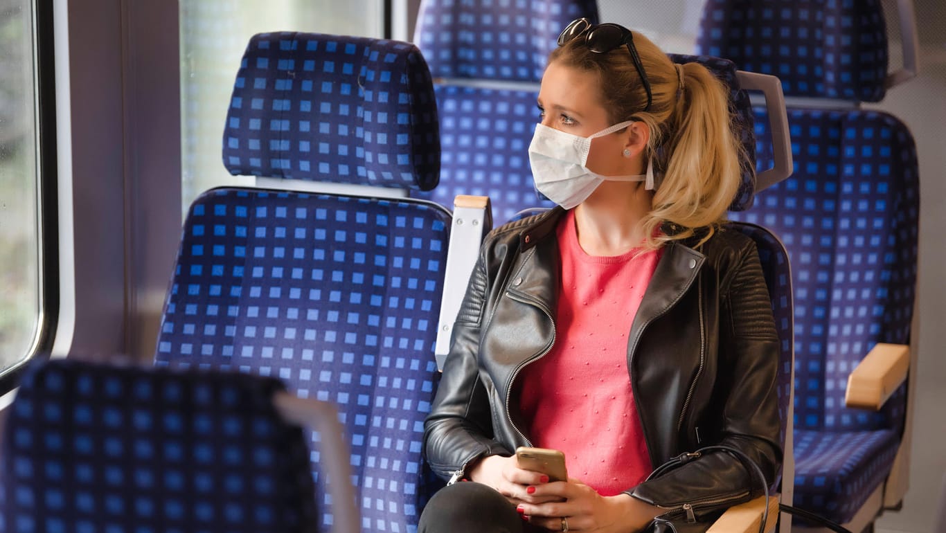 Frau mit Mund-Nasenschutz im Zug: Die eigenen Mitarbeiter sollen vom Bund einen zweiten Sitzplatz finanziert bekommen (Symbolbild).