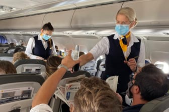 Eine Lufthansa-Stewardess reicht ein Getränk weiter (Archivbild): Die Airline stampft den Bordservice weiter ein.