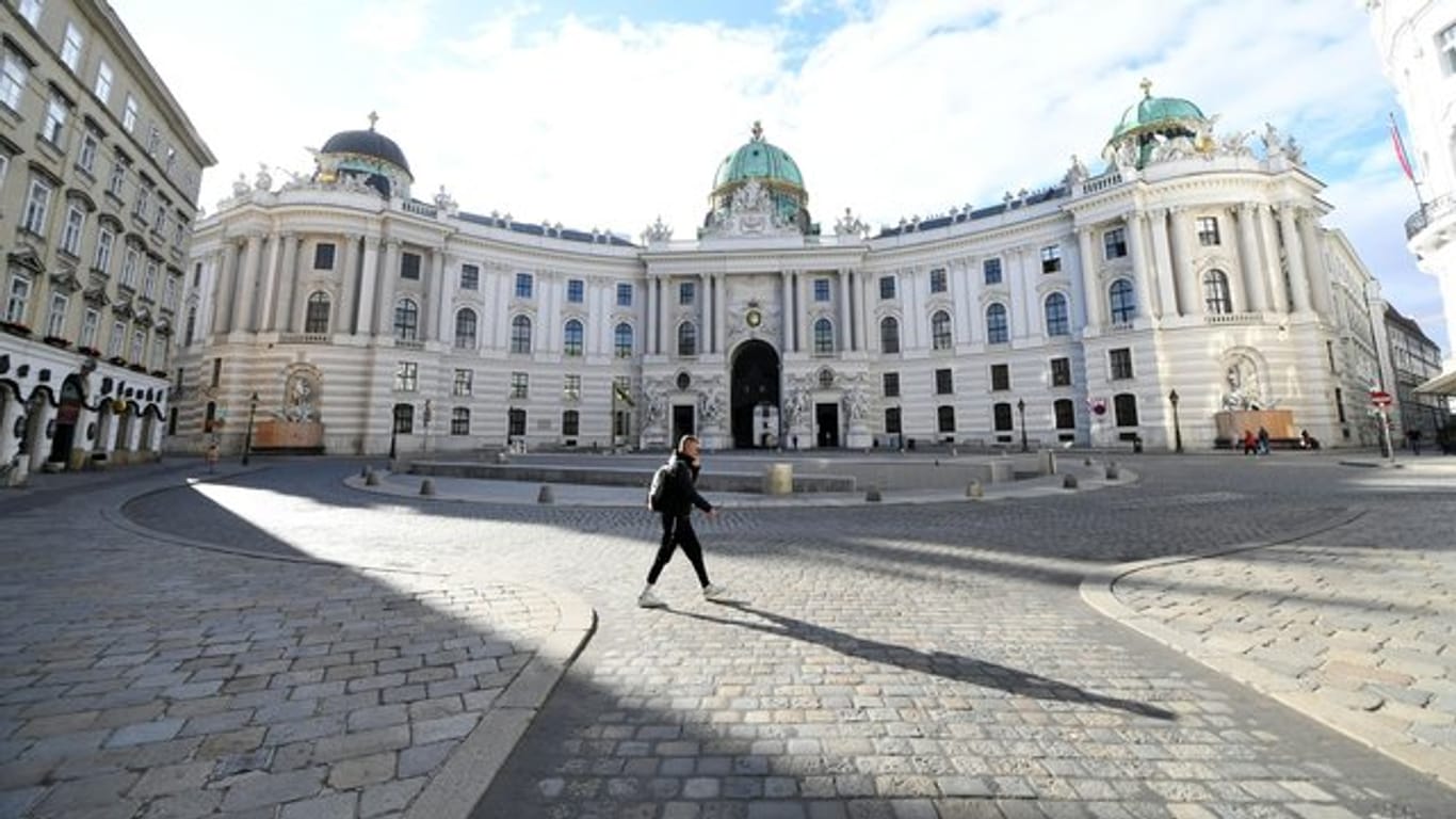 Ein Mann geht über den leeren Michaelerplatz in Wien.