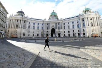 Ein Mann geht über den leeren Michaelerplatz in Wien.
