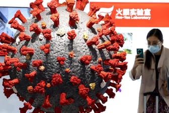 Eine Frau macht ein Foto von einem Covid-19-Modell: Etwa 4.700 Menschen starben in China bislang am Coronavirus.