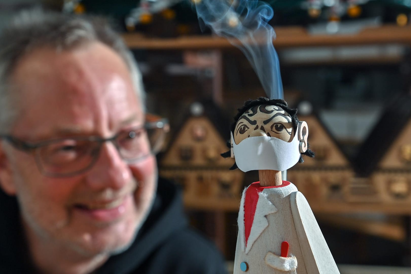 Sachsen, Seiffen: In der Werkstatt des Spielzeugmachers Tino Günther in Seiffen raucht der neuesten Figur des Sortiments der Kopf. Der Virologen-Räuchermann erinnert an den Charité-Virologen Drosten.