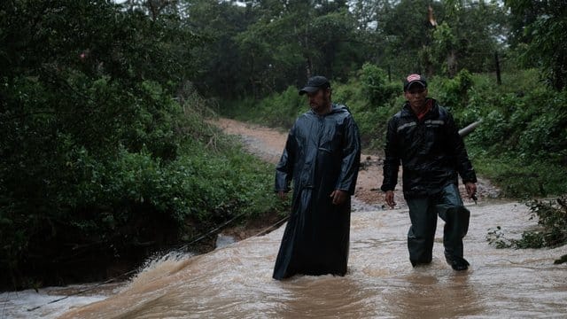 Zwei Männer überqueren in Nicaragua einen reißenden Fluss.