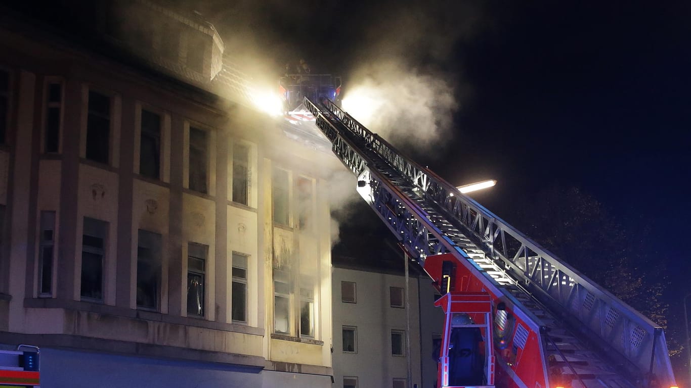 Feuerwehrkräfte versuchen mithilfe einer Feuerwehrleiter einen Brand in einem Mehrfamilienhaus zu löschen: Bei dem Feuer wurden sechs Personen verletzt.
