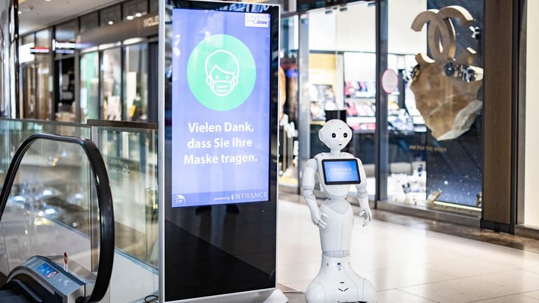 Ein Roboter der Firma Entrance Robotics steht in einem Düsseldorfer Einkaufszentrum an der Kö: Er erinnert Kunden an die Maskenpflicht.
