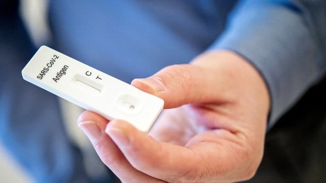 Ein Mann hält einen Schnelltest zur Erkennung des Coronavirus in den Händen. Ein Mann hält einen Schnelltest zur Erkennung des Coronavirus in den Händen.