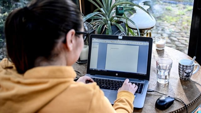 Eine junge Frau arbeitet im Homeoffice in einem Wintergarten. Eine junge Frau arbeitet im Homeoffice in einem Wintergarten.