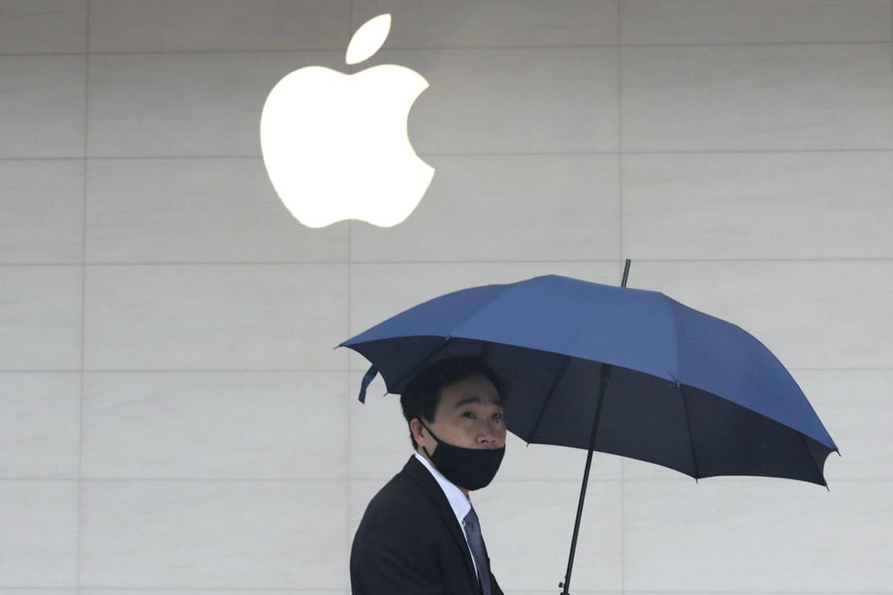 Ein Mann mit Regenschirm läuft an einem Apple Store vorbei: Apple erhöht nach eigenen Aussagen den Datenschutz für seine Nutzer.