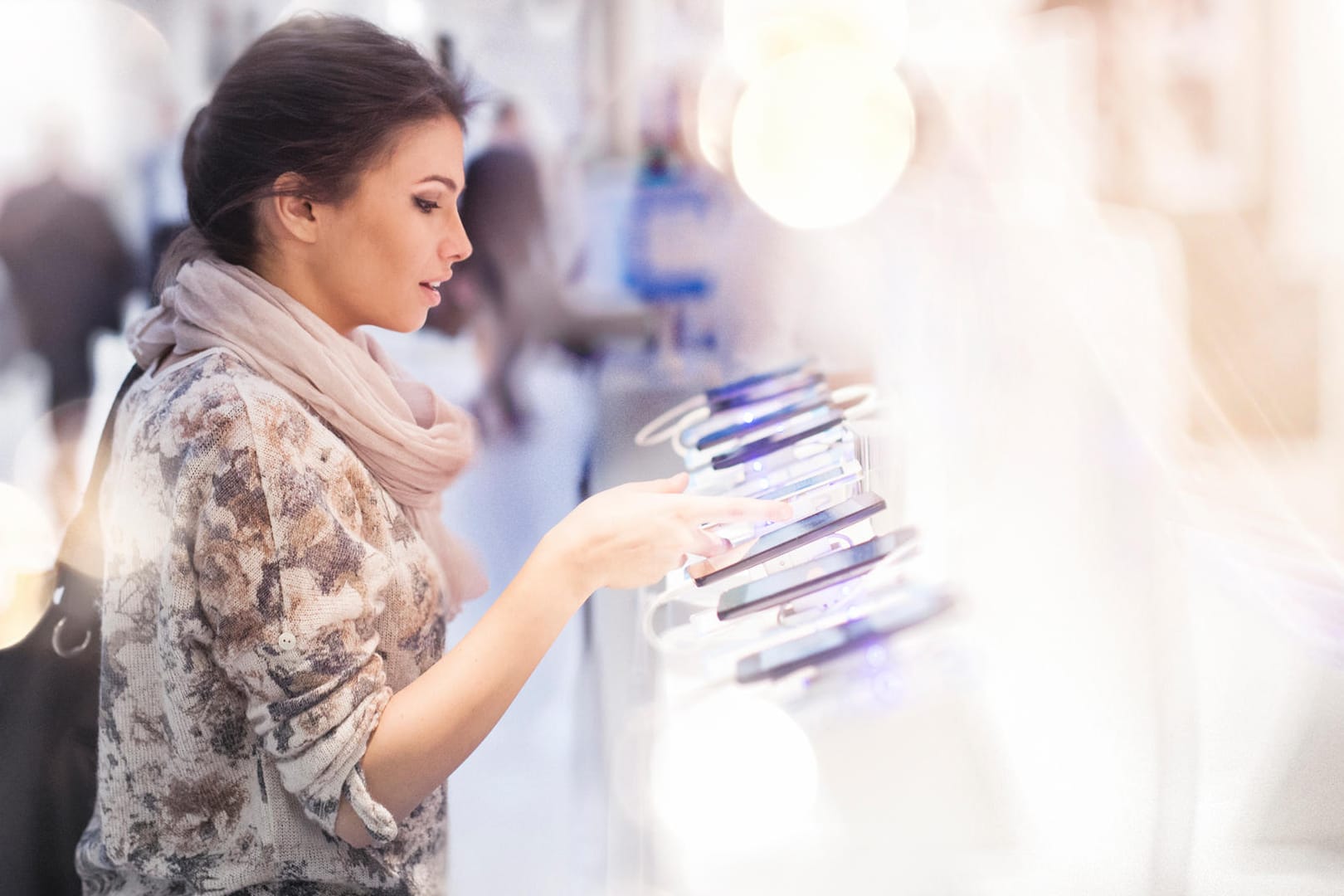 Eine Frau sieht sich Smartphone-Modelle in einem Elektronikmarkt an: Ein neues Handy kostet heute deutlich mehr als noch vor fünf Jahren.