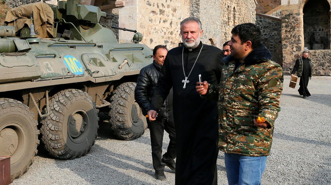 Pater Hovhannes neben einem russischen Militärfahrzeug: Russland entsendet knapp 2.000 Friedenssoldaten für fünf Jahre nach Bergkarabach.