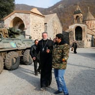 Pater Hovhannes neben einem russischen Militärfahrzeug: Russland entsendet knapp 2.000 Friedenssoldaten für fünf Jahre nach Bergkarabach.