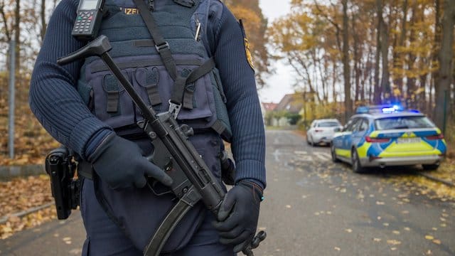 Ein Polizist mit schwerem Geshütz bewacht die Zufahrt zu einem Wohnviertel, indem zwei Menschen erschossen worden sind. Ein Polizist mit schwerem Geshütz bewacht die Zufahrt zu einem Wohnviertel, indem zwei Menschen erschossen worden sind.
