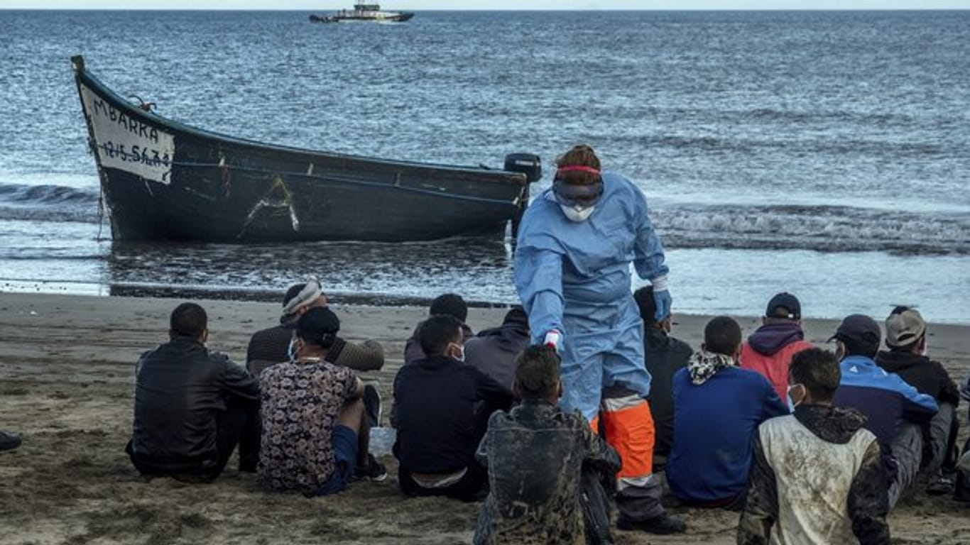 Migranten aus Marokko lassen ihre Temperatur messen, nachdem sie mit einem Holzboot an der Küste von Gran Canaria angekommen sind.
