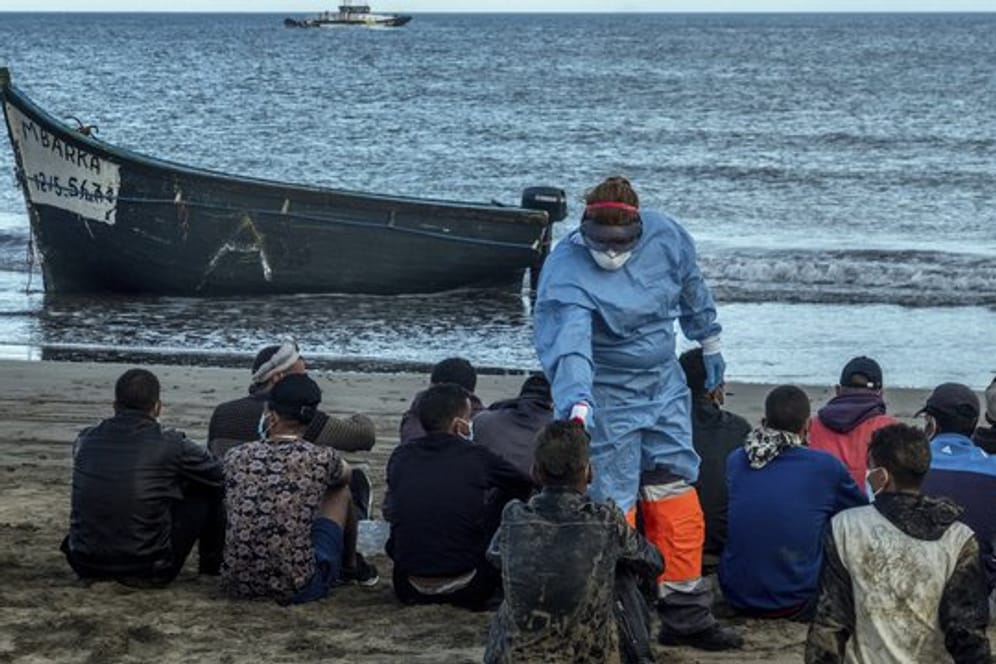Migranten aus Marokko lassen ihre Temperatur messen, nachdem sie mit einem Holzboot an der Küste von Gran Canaria angekommen sind.