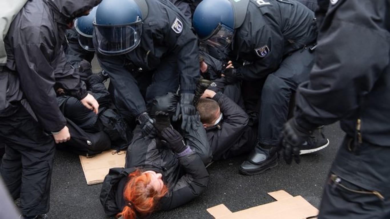 Polizisten lösen eine Sitzblockade von Gegen-Demonstranten auf.