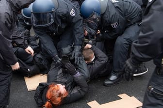 Polizisten lösen eine Sitzblockade von Gegen-Demonstranten auf.