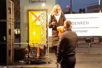 Ein Mann drückt einer Rednerin auf einer "Querdenken"-Demonstration eine Warnweste in die Hand: Sie hatte sich zuvor mit Sophie Scholl verglichen.