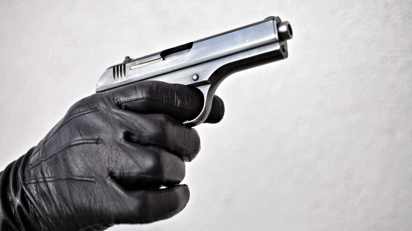 Eine Person hält eine Pistole in der Hand (Symbolbild): In Köln haben zwei Bewaffnete einen Supermarkt überfallen.