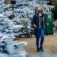 Ein Frau mit Maske betrachtet in den Niederlanden weihnachtlich dekorierte Tannenbäume: Auch bei einem Lockdown sollten Sie im Corona-Winter in Bewegung bleiben.