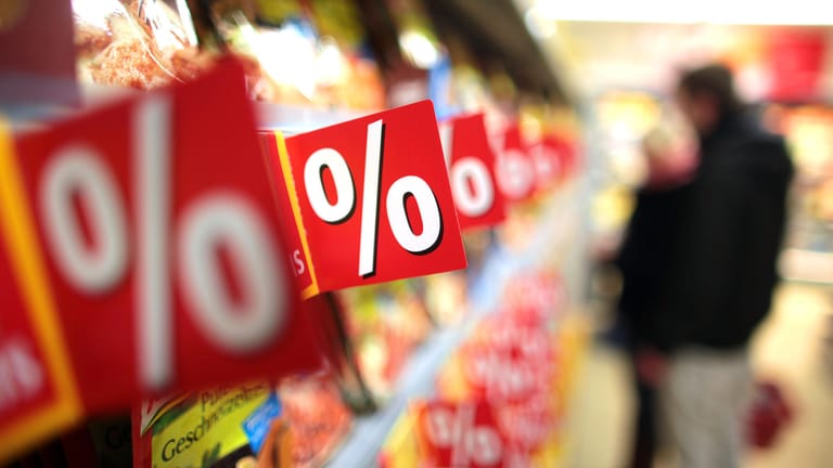 Prozentzeichen hängen in einem Supermarkt an Regalen: Im Lebensmittelhandel sind derzeit wieder einige Artikel rabattiert.