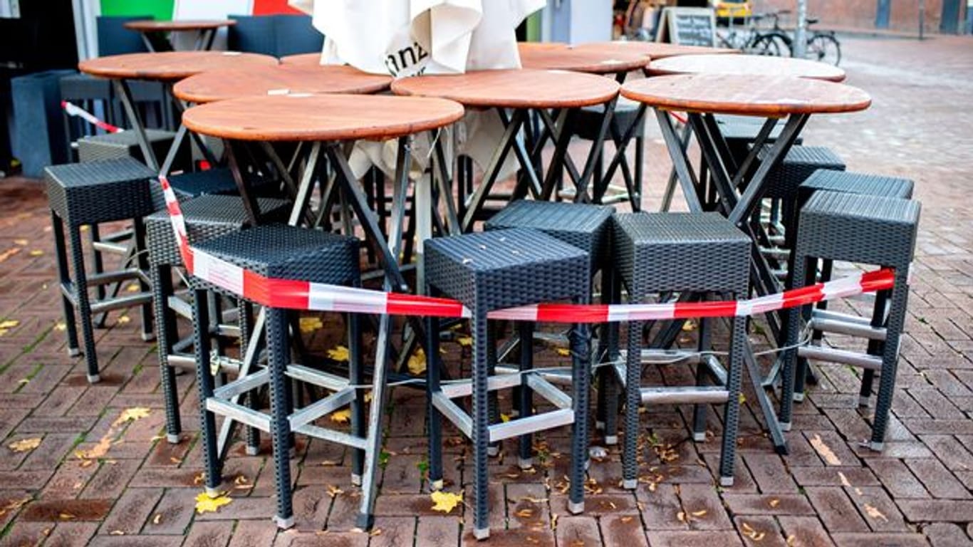 Tische und Stühle stehen abgesperrt vor einer Pizzeria in Hannover.