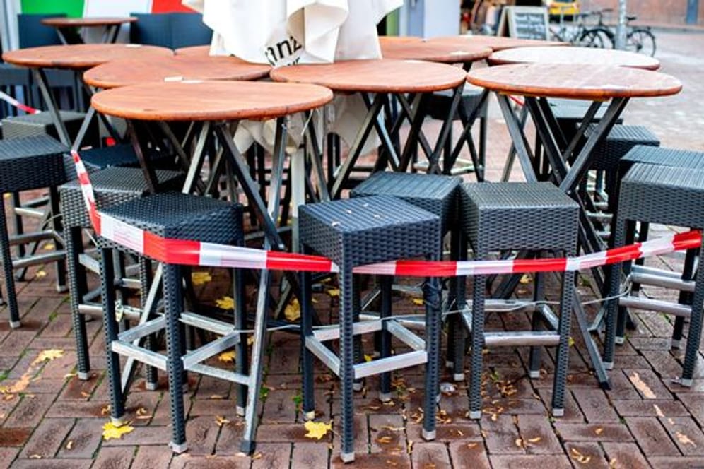 Tische und Stühle stehen abgesperrt vor einer Pizzeria in Hannover.