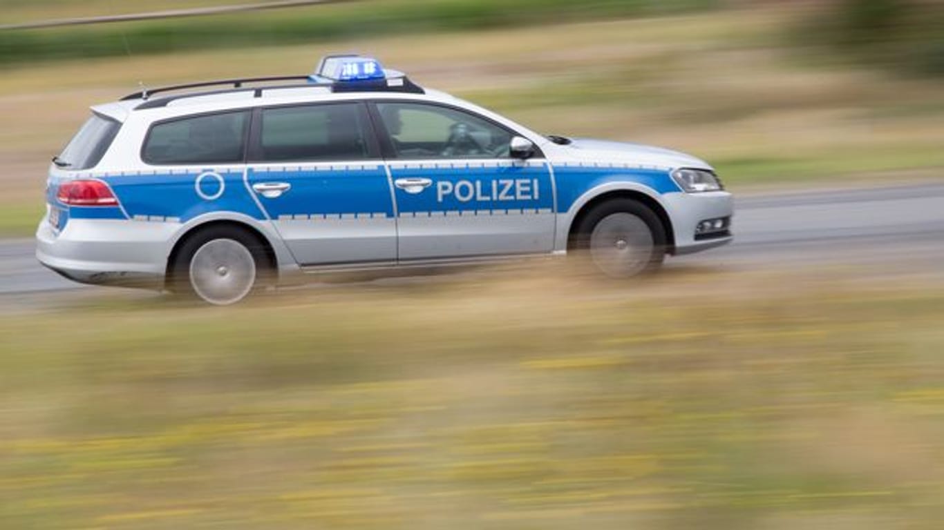 Ein Polizeifahrzeug fährt mit Blaulicht auf der Landstraße