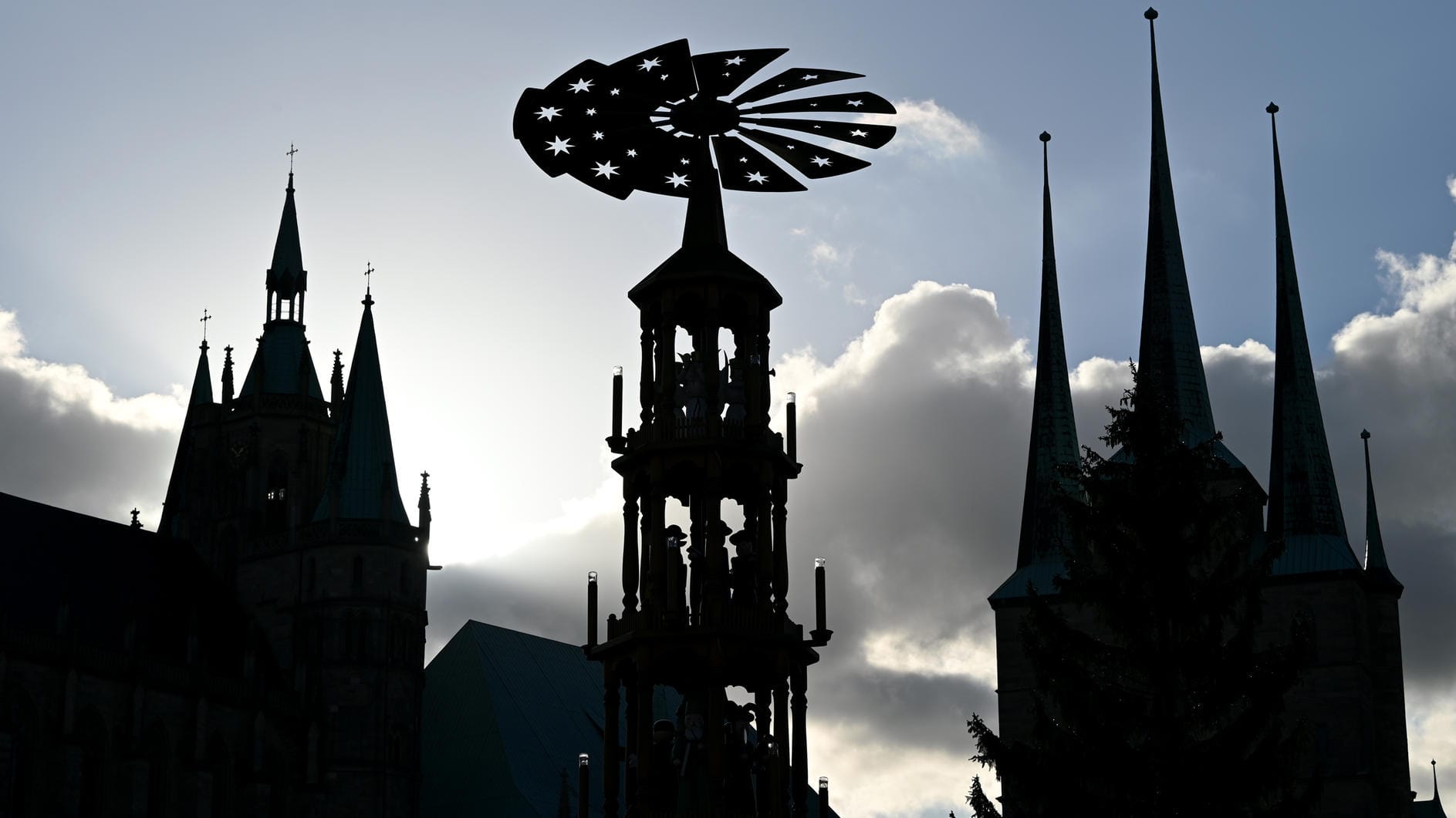 Die Silhouette der Weihnachtspyramide auf dem Domplatz ist neben dem Mariendom zu sehen: An einigen Traditionen wird in Erfurt trotz Corona-Pandemie festgehalten.