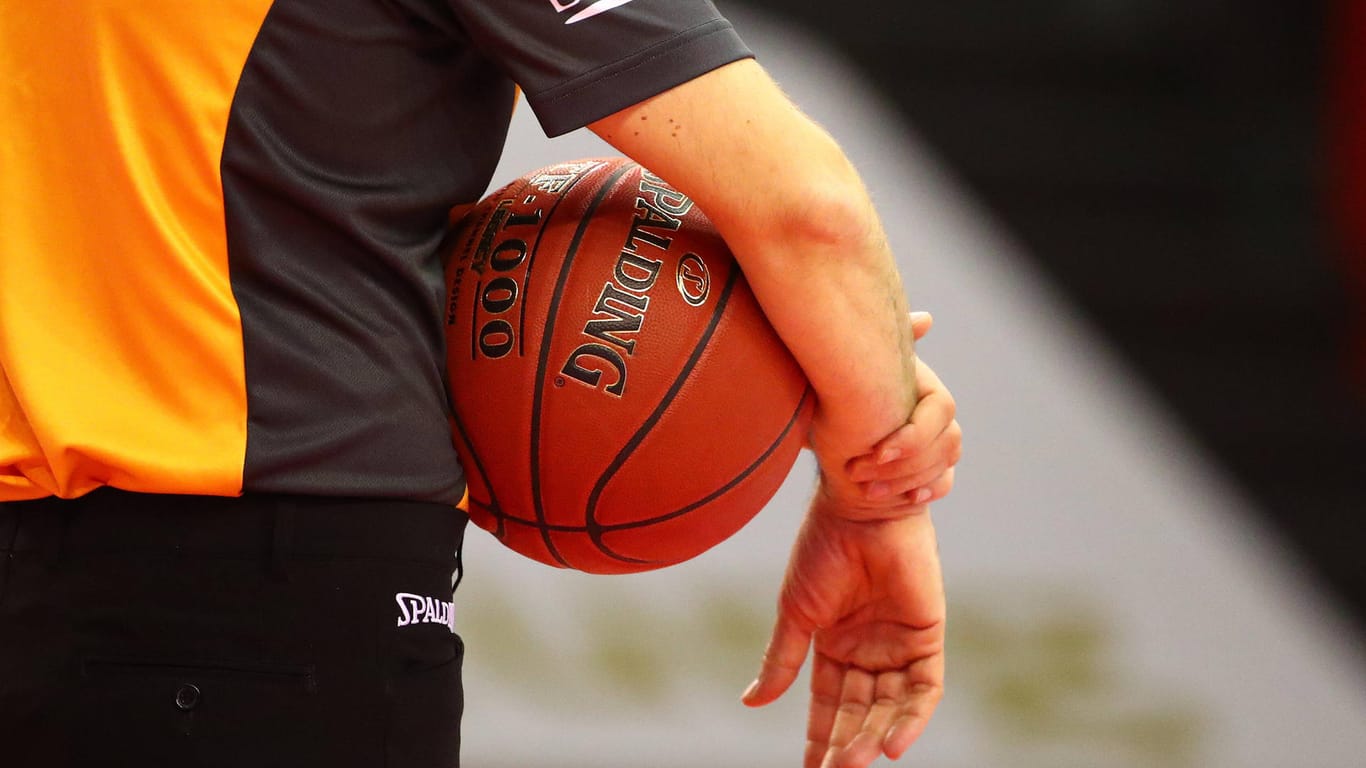 Ein Mann hält einen Basketball in der Hand (Symbolbild): Phoenix Hagen muss wegen mehrwöchiger Quarantäne seiner Spieler nun eine Partie absagen.