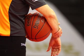 Ein Mann hält einen Basketball in der Hand (Symbolbild): Phoenix Hagen muss wegen mehrwöchiger Quarantäne seiner Spieler nun eine Partie absagen.