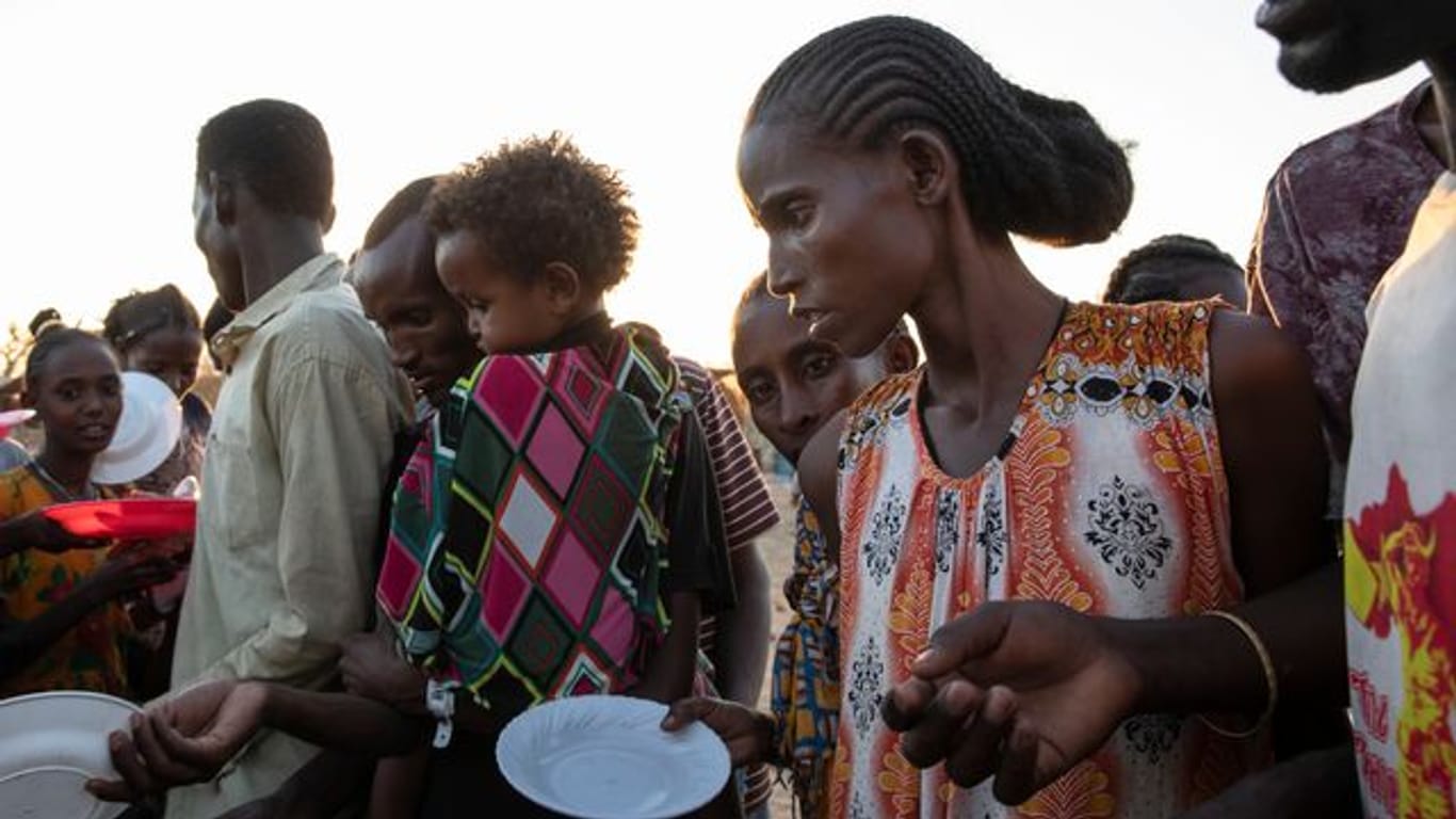 Menschen, die vor dem Konflikt in der äthiopischen Region Tigray geflohen sind, warten auf gekochten Reis in dem sudanesischen Flüchtlingslager Um Rakuba.