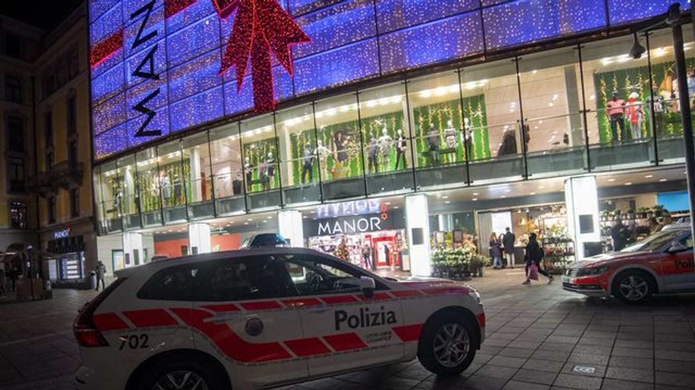 Polizeifahrzeuge stehen vor dem Kaufhaus Manor an der Piazza Dante im schweizerischen Kanton Tessin: Eine Frau hat in dem Warenhaus heute zwei Passantinnen mit einem Messer angegriffen.
