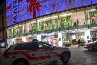 Polizeifahrzeuge stehen vor dem Kaufhaus Manor an der Piazza Dante im schweizerischen Kanton Tessin: Eine Frau hat in dem Warenhaus heute zwei Passantinnen mit einem Messer angegriffen.