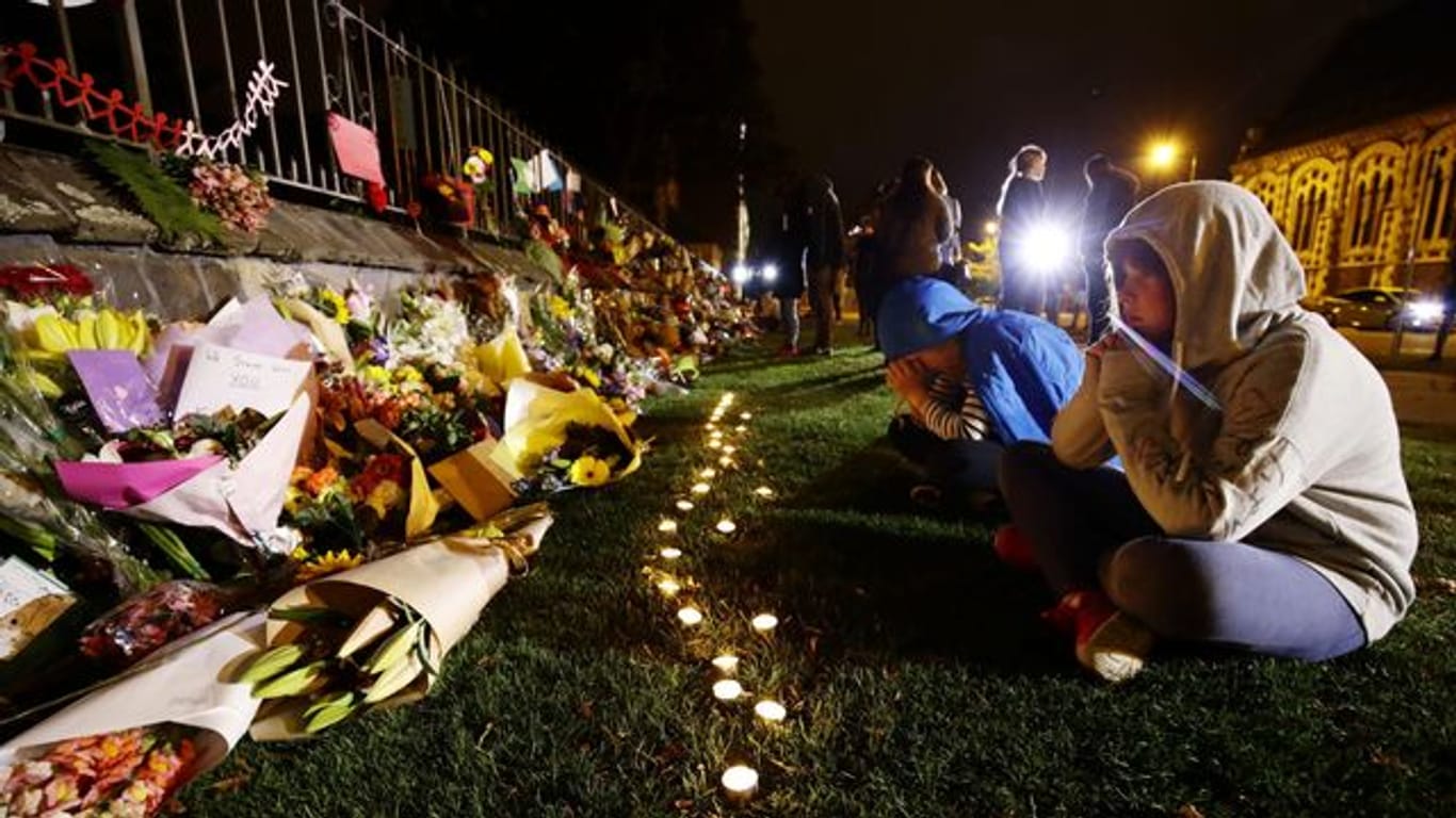 Menschen trauern vor Kerzen und Blumen, die in Gedenken an die Opfer der Anschläge auf zwei Moscheen in Christchurch, Neuseeland niedergelegt wurden.