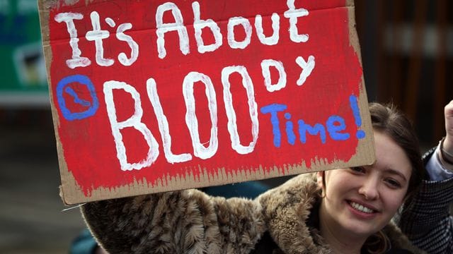 Eine Frau in Edinburgh hält bei einer Kundgebung ein Schild mit der Aufschrift "It's about bloody time!" (dt. Eine Frau in Edinburgh hält bei einer Kundgebung ein Schild mit der Aufschrift "It's about bloody time!" (dt.