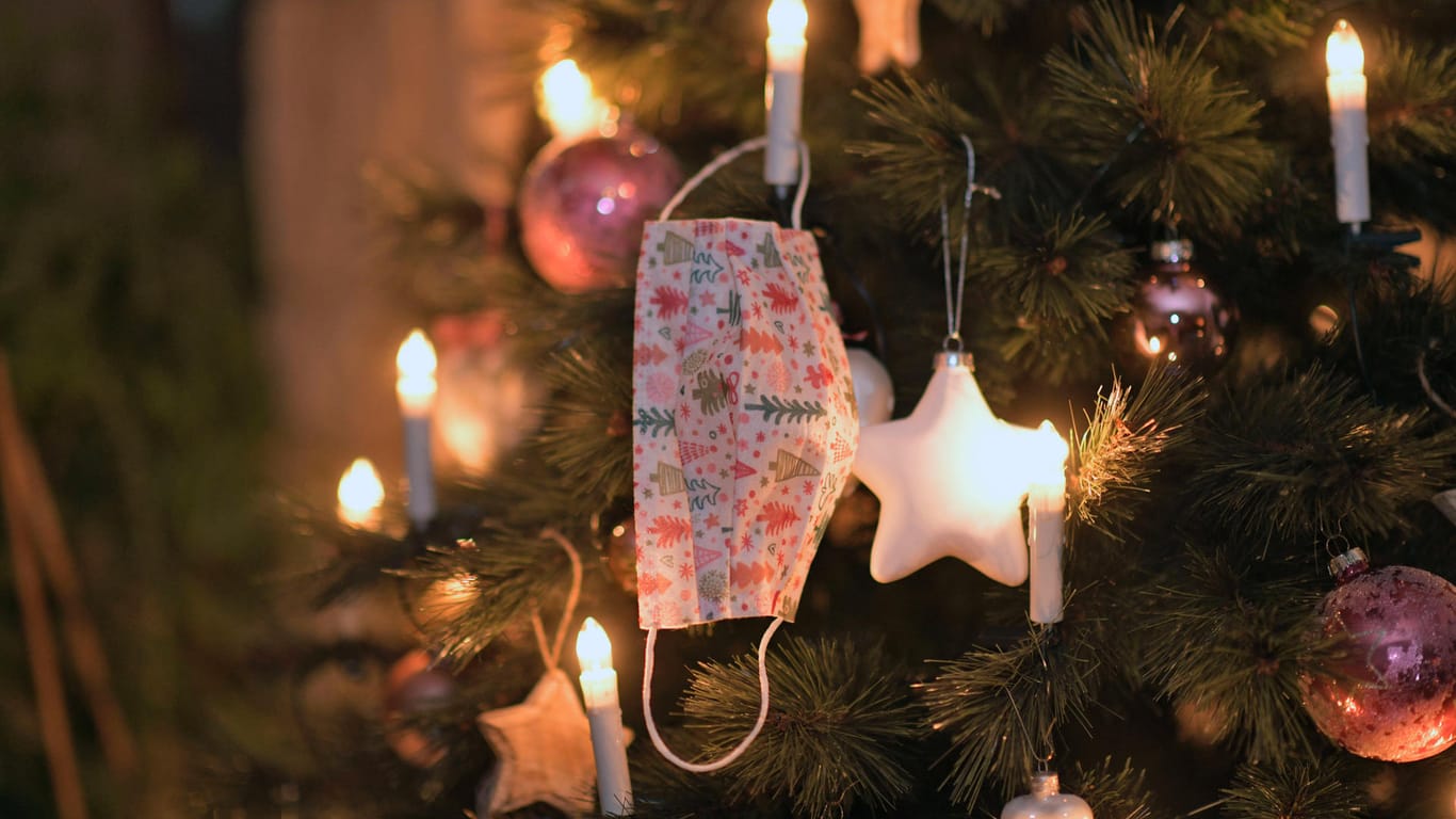 Ein Mund-Nasen-Schutz hängt an einem Weihnachtsbaum (Symbolbild): Wegen Corona fällt das Weihnachtsfest dieses Jahr anders aus, der Barmer Kulturadvent hat sich dennoch etwas einfallen lassen, um Stimmung zu verbreiten.