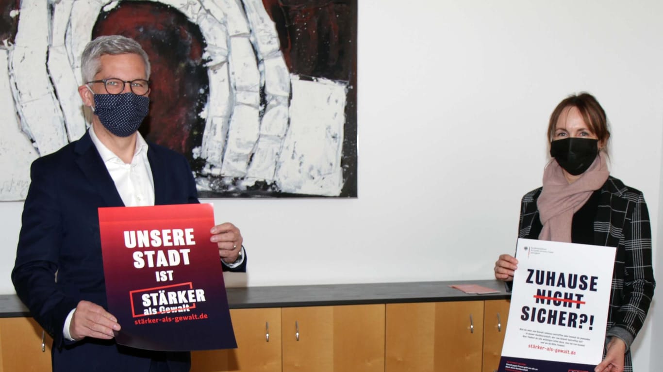 Oberbürgermeister Erik O. Schulz (li.) und Sabine Michel als Vertreterin des Runden Tischs gegen häusliche Gewalt halten Plakate hoch: Sie wollen gemeinsam ein Zeichen gegen Gewalt an Frauen setzen.