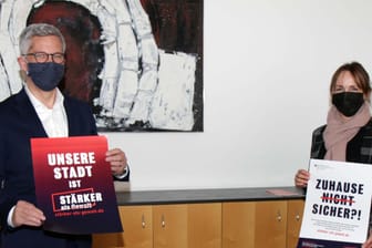 Oberbürgermeister Erik O. Schulz (li.) und Sabine Michel als Vertreterin des Runden Tischs gegen häusliche Gewalt halten Plakate hoch: Sie wollen gemeinsam ein Zeichen gegen Gewalt an Frauen setzen.