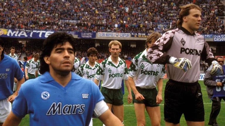 Diego Armando Maradona führt als Kapitän den SSC Neapel gegen Werder Bremen um Torwart Oliver Reck (re.) aufs Feld des Stadio San Paolo.